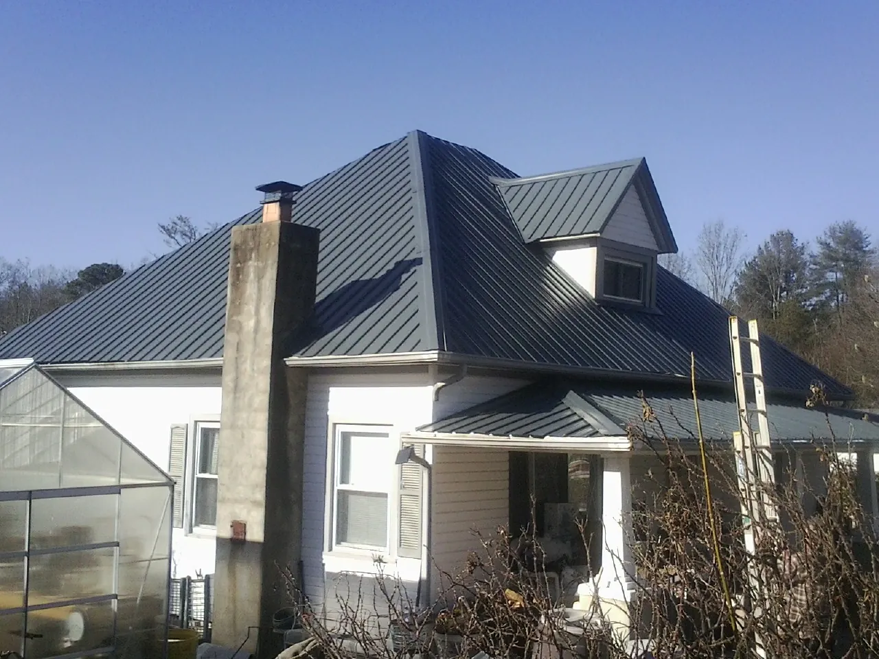 Dark blue standing seam metal roof on a white farmhouse with dormer — Slate & Tile Roof Repair by Roofing Brothers in Puyallup