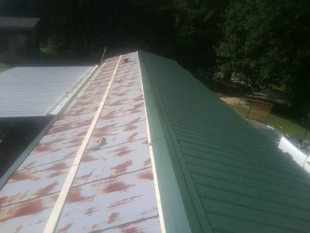 Old rusted panels beside newly installed green metal roofing — Wind Damage Roof Repair by Roofing Brothers in Puyallup