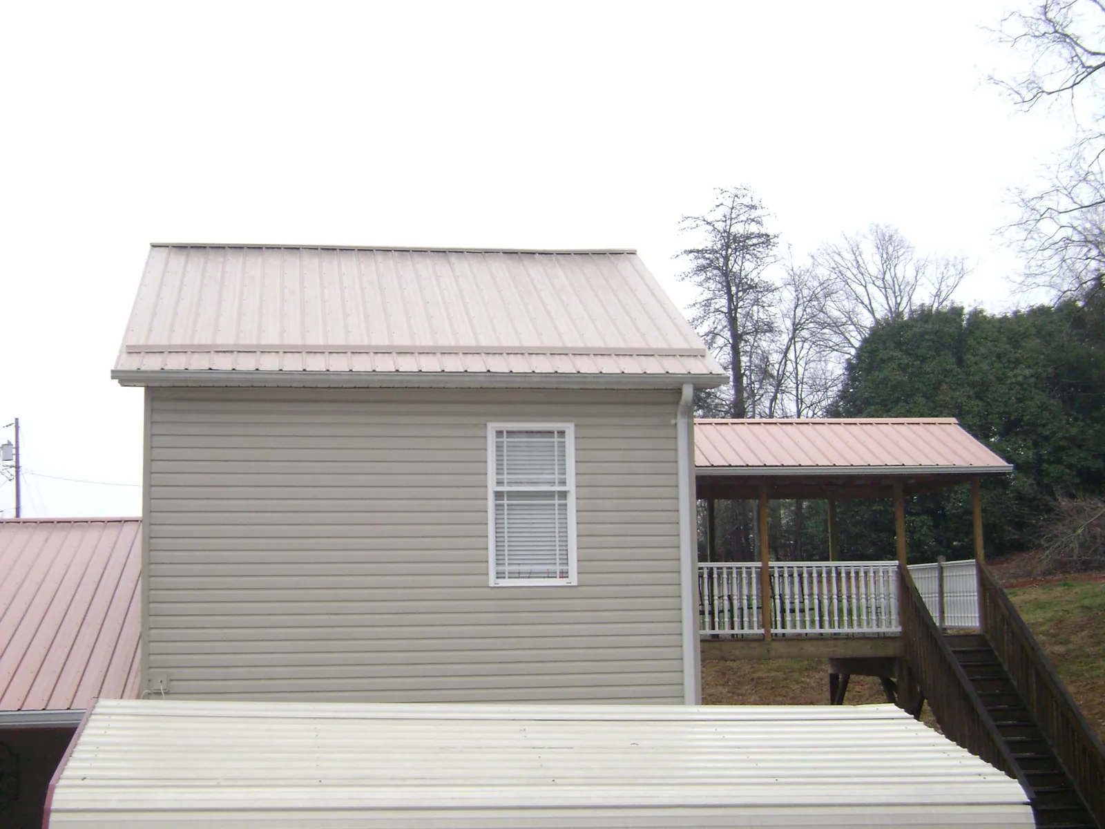 Tan metal roofs on a two story addition and attached porch, from a Roof Replacement job in Puyallup