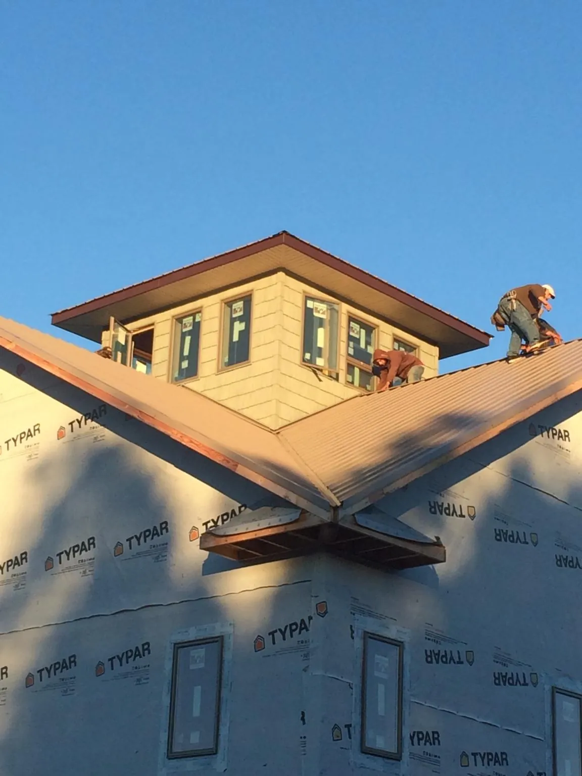 Roofers working around a rooftop cupola on a new metal roof at sunset — Roof Waterproofing in Puyallup by Roofing Brothers
